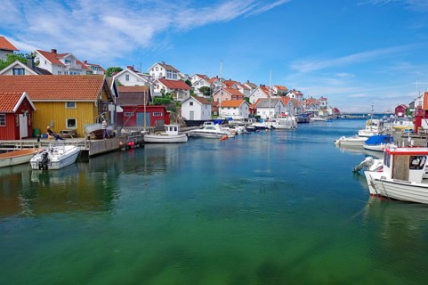 Colourful houses on the water with several boats, under a sunny sky, idyll, crystal clear water,
