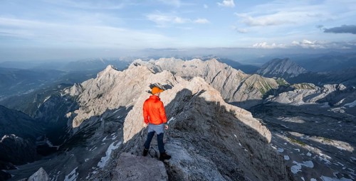 Mountaineer on a narrow rocky steep ridge, view of the Höllental and the Alpspitze from the