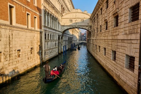View from 'Ponte della paglia' on the bridge 'Bridge of Sighs' over a waterway on a sunny morning