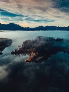 Autumn sunrise in the foothills of the Alps with fog at Illasbergsee and Forggensee near Halblech