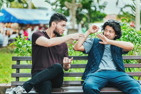 Young man sitting refusing a cigarette in the park. Disgusted guy sitting refusing a cigarette