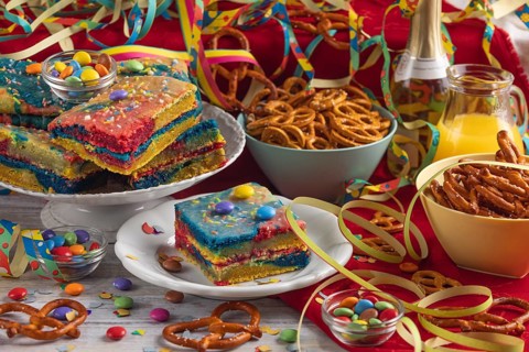 Colourful cakes and pretzels alongside drinks and party decorations, carnival