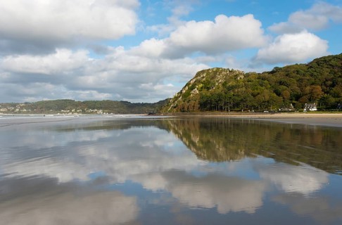 Beach with mountain backdrop and clouds reflected in the calm water, Plage Saint Efflamm, Le Grand