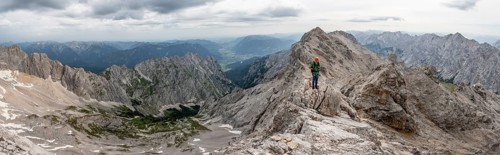 Panorama, mountaineer with helmet on a narrow rocky ridge at sunrise, crossing the Jubiläumsgrat,