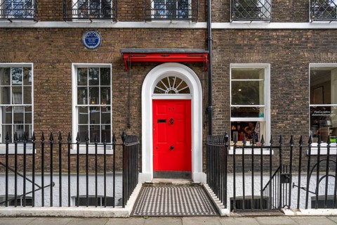 Red entrance door in a brick building with a cast-iron fence, Charles Dickens Museum, 48-49 Doughty