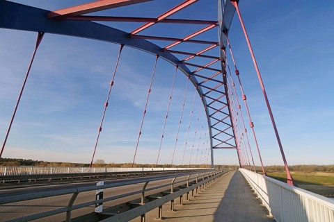 Modern bridge with blue and red struts under a clear sky, symbol of German unity, Dömitzer Brücke,