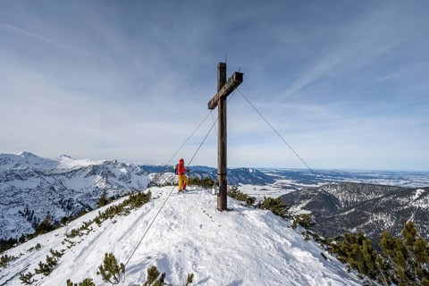 Ski tourer at the summit of the Simetsberg with summit cross, mountain panorama, Estergebirge,