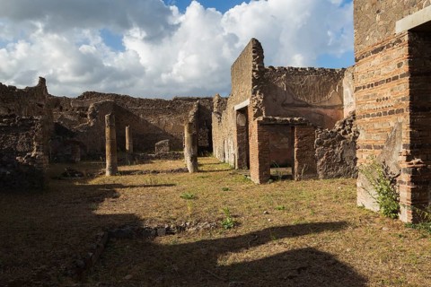 Remnants of old residential building walls with doorways made of terracotta bricks and stones plus