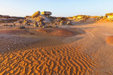 Striking cliffs surrounded by windswept sand structures, Huqf stone desert, Arabian Peninsula,