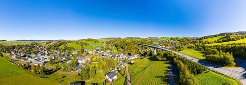Aerial view of the village in autumn with Markersbach viaduct and bridge of the federal road 101