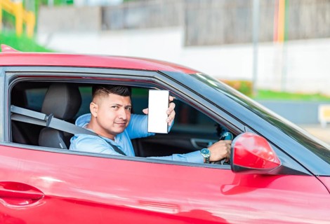Smiling male driver showing cell phone screen. Handsome driver showing cell phone screen outdoors