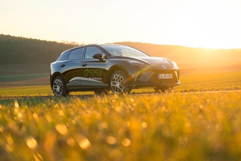 Black SUV parked in a meadow at sunset, natural surroundings, e-car sharing vehicle from Deer