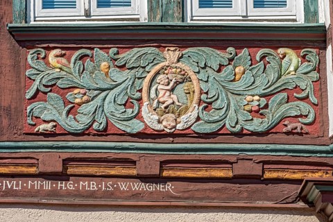 Colourfully painted carvings, medallion with putti, paradise, floral ornaments, half-timbered house