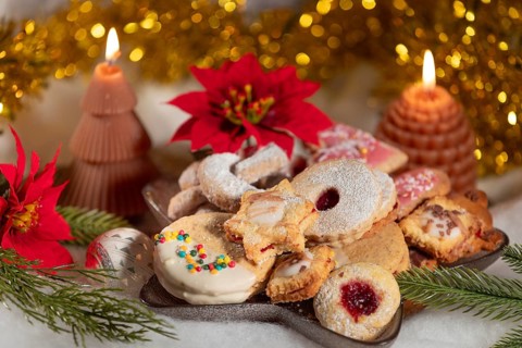 A plate full of biscuits surrounded by candles and red poinsettias