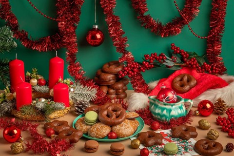Table with Christmas decorations, biscuits and Advent wreath with red candles, framed by garlands