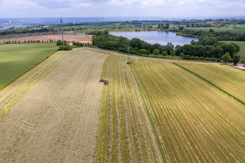 Aerial view of the Oberwartha reservoir, in the foreground a tractor with rake swathing hay,