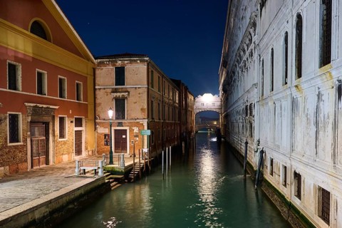 View from 'Ponte della paglia' on the bridge 'Bridge of Sighs' over a waterway in Venice by night