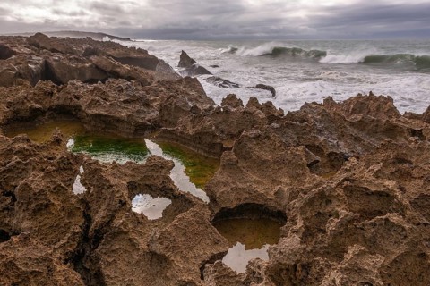 The rocks are scattered throughout the area, with some of them being large and jagged. The water