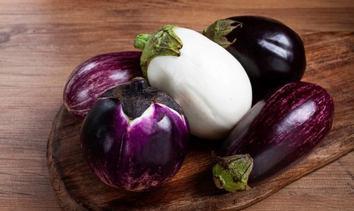 Colored eggplants, on a wooden table, white, purple and black eggplants, top view, raw eggplants,