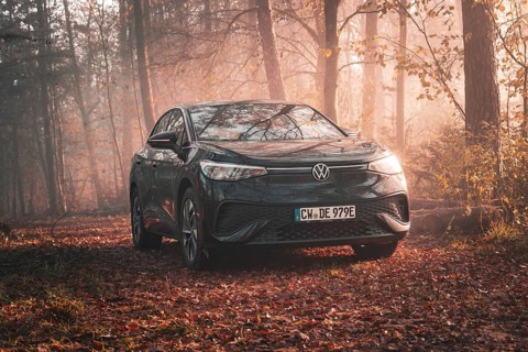A Volkswagen is located in an autumnal misty forest and is illuminated by the evening light,