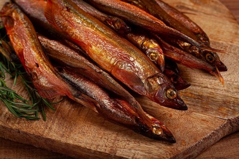 Cold smoked capelin, on a wooden chopping board, no people