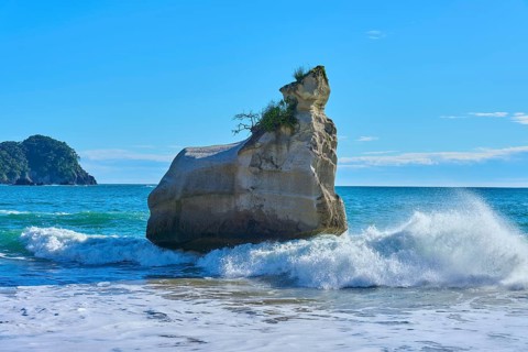 Energetic waves crash against a huge rock in the sea, Cathedral Cove, Hahei, Coromandel Peninsula,