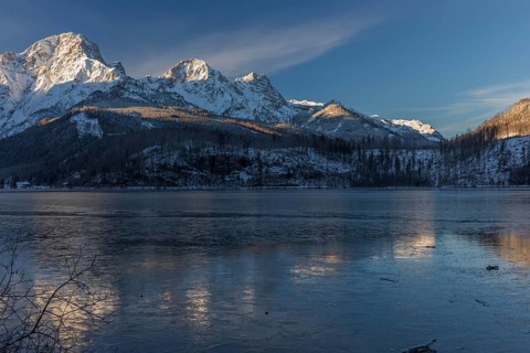Lake Almsee in winter. Snow on the mountains and a clear blue sky. Perfect reflection on the lake
