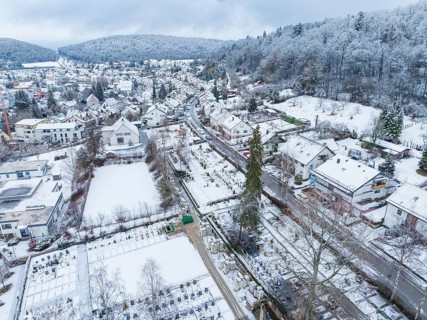 Snow-covered landscape of a village with houses, trees and a cemetery in winter, Aidlingen,