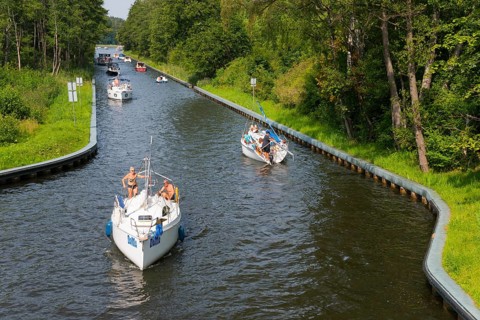 Boats glide along a tree-lined canal surrounded by summer nature, Gizycko, Warminsko-Mazurskie,
