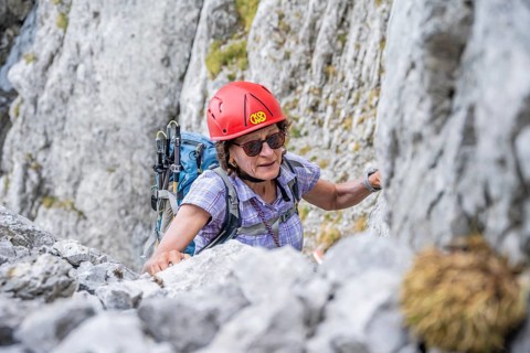 Female mountaineer with helmet climbing a rock face, ascent to the Ackerlspitze, Wilder Kaiser,