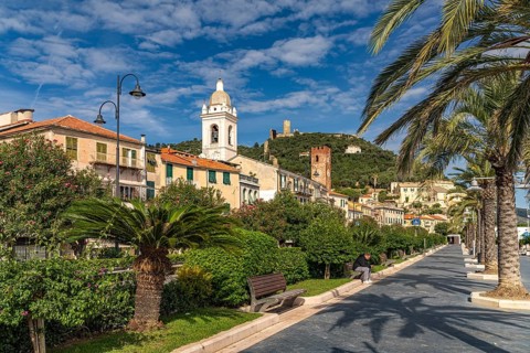 Palm trees on the promenade and cathedral of Noli, Riviera di Ponente, Liguria, Italy, Europe