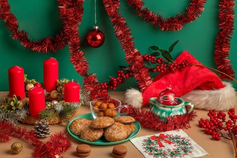 Table with Christmas decorations, biscuits and Advent wreath with red candles, framed by garlands