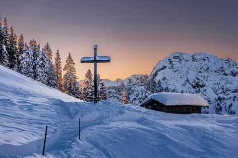 Hut and summit cross, sunrise snow tour on the Tegelberg in the Allgäu in Bavaria. Winter Wonder