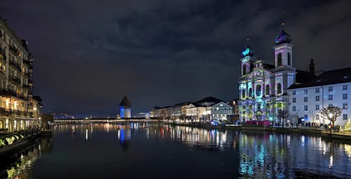 Water tower and Jesuit church on the right with light installation, on the Reuss at dusk, Old Town,