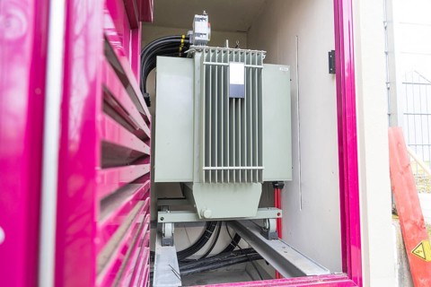 Transformer in a pink housing with grey paint in a technical environment, switch cabinet