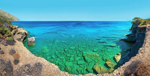 Clear blue water meets rocky coastline under a blue sky, hiking trail from Avlona to Diafani,