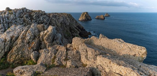 The tip of Pen Hir and its peach stacks. The rocks are jagged and rough, while the water is calm.