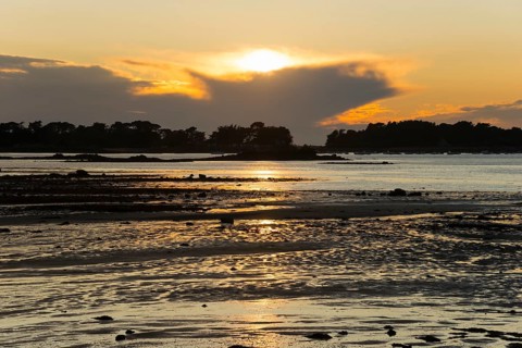 Sunset over the sea with golden reflections and coastal silhouette, Plage de Raluzet, Plougrescant,