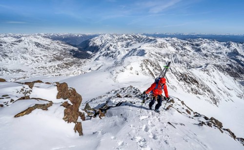 Ski tourers on foot, carrying skis on a rucksack, mountain panorama, snow-covered mountain