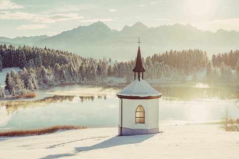 Chapel by the lake in the wintry snow-covered Allgäu near Halblech in front of an impressive