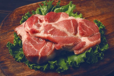 Raw pork steak, two pieces, on a wooden background