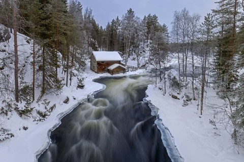 Old wooden Myllykoski water mill along the river Kitkajoki in winter, Oulanka National Park,