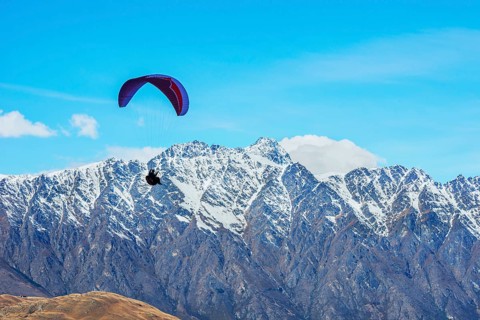 Paragliding over the snowcapped Remarkables mountain range, Queenstown, South Island, New Zealand,