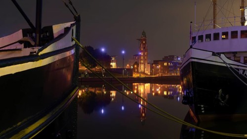 View over the new harbour to the Simon Loschen lighthouse through two moored ships in Bremerhaven