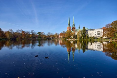 Mill pond with general buildings, Lübeck Cathedral, ducks and trees, symmetrical reflections on the