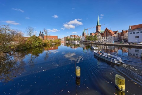 River Trave with quay wall, historic houses, Lübeck Holstentor, church towers of St. Marien and St.