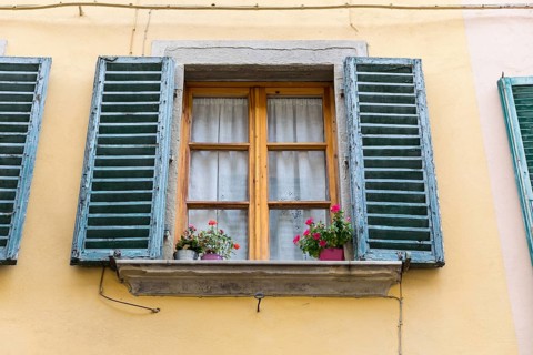 Wooden windows with flower pots and blue shutters in the medieval old town centre of Arezzo,