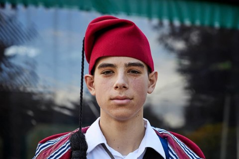 Young man in traditional Cretan dress with red hat, serious expression, visit of the Federal