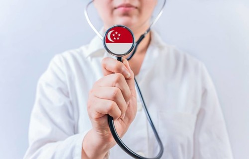 Doctor holding stethoscope with Singapore flag. National Health System of Singapore
