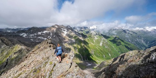 Mountaineer on a steep rocky ridge, on the summit of the Lasörling, view of the mountain panorama